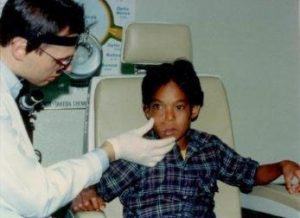 Here Dr. Szachowicz examines a young boy with a mass growing in his right cheek.