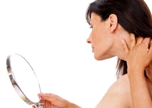 Woman looking in mirror at jawline